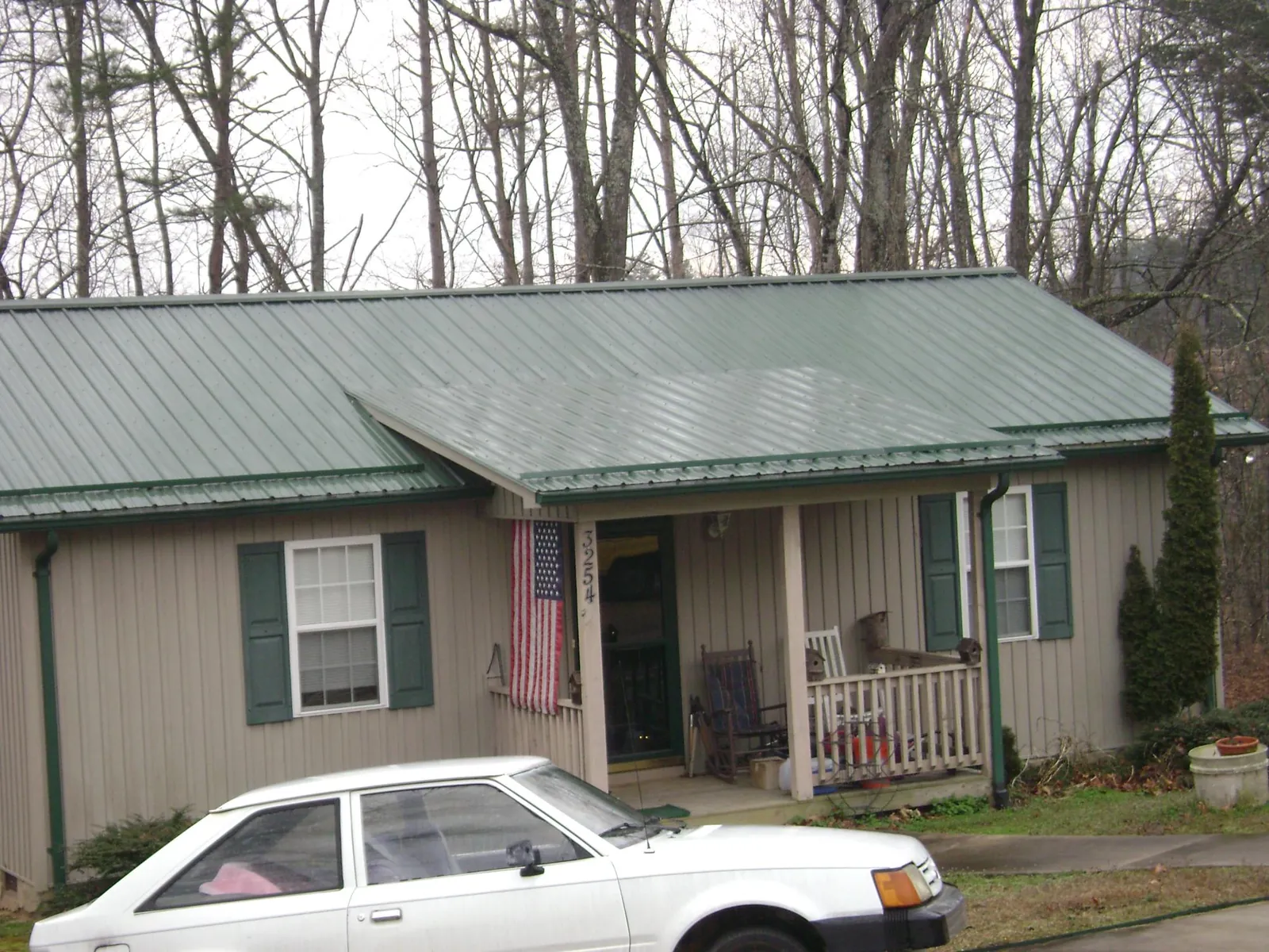 Green metal roof and front porch on a tan sided cottage in Springfield